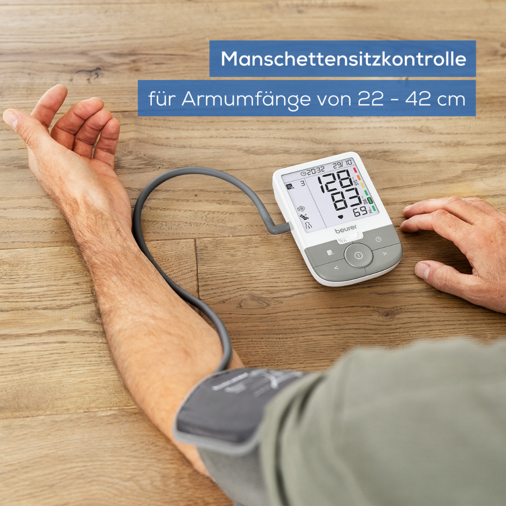 Eine Person verwendet ein Beurer Oberarm-Blutdruckmessgerät BM 53 | Packung (1 Stück) der Beurer GmbH am linken Arm. Die Manschette wird am Oberarm angelegt und der Monitor zeigt Blutdruckwerte und Arrhythmieerkennung an. Der Text auf Deutsch lautet „Manschettensitzkontrolle für Armumfänge von 22 – 42 cm.“