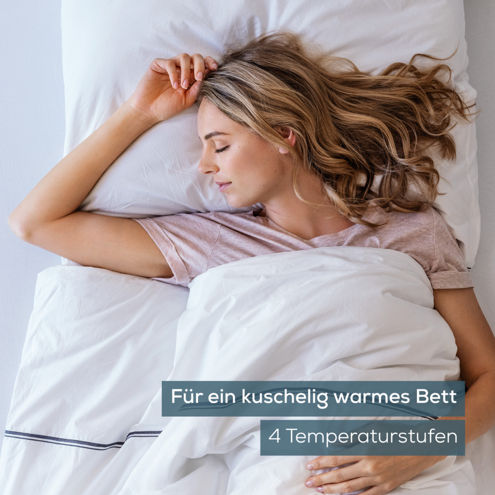 Eine Frau mit langen Haaren schläft auf der Seite im Bett, trägt ein helles Hemd und ist mit einer weißen Decke zugedeckt. Der Text auf dem Bild lautet „Für ein kuschelig warmes Bett, 4 Temperaturstufen“ und hebt das Beurer Wärmeunterbett UB 60 | Packung (1 Stück) der Beurer GmbH hervor, das Komfort gewährleistet und dem OEKO-TEX® STANDARD 100 entspricht.