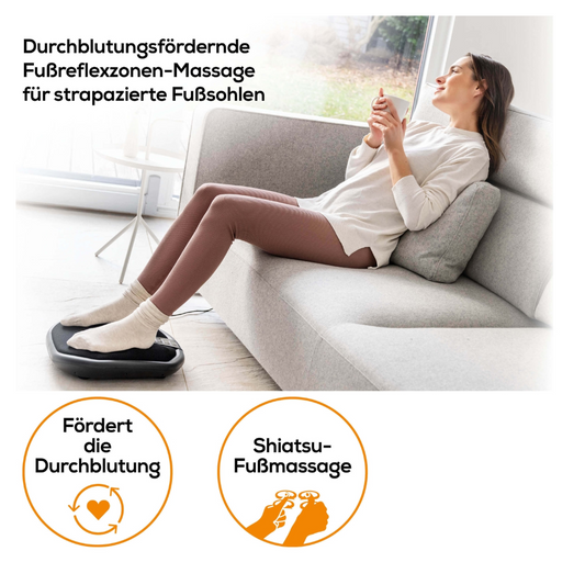 Eine Frau entspannt sich auf einer grauen Couch und benutzt das Beurer FM 70 Shiatsu Fuß- und Rückenmassagegerät mit zuschaltbarer Wärmefunktion. In ihren Händen hält sie eine Fernbedienung. Sie trägt ein weißes Oberteil und eine rosa Hose. Zwei Symbole unten beschreiben die Vorteile: verbesserte Durchblutung und Shiatsu-Fußmassage. Es wird deutscher Text mit dem Markennamen Beurer GmbH angezeigt.