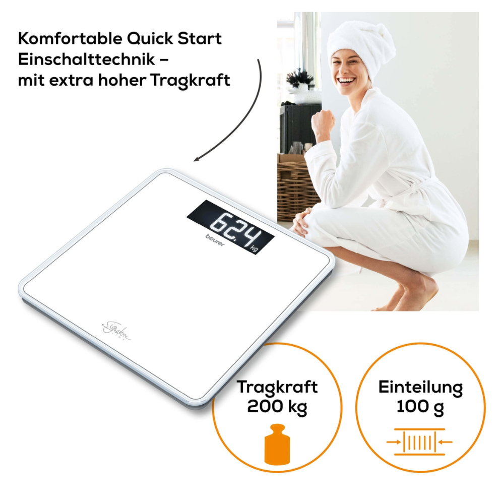 Eine Person in weißem Bademantel und Handtuch hockt lächelnd neben einer Beurer GS 400 Körperwaage SignatureLine, die 62,4 kg anzeigt. Der Text hebt die Funktionen der Waage hervor: Quick Start-Technologie, große Plattform aus Sicherheitsglas, hohe Gewichtskapazität (200 kg) und präzise Messung (100-g-Schritte).