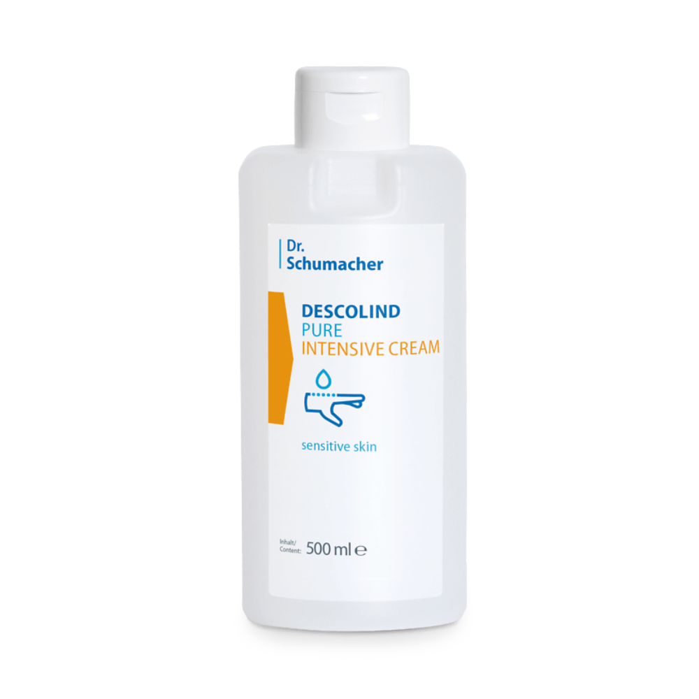 Eine 500-ml-Flasche Dr. Schumacher Descolind Pure Intensiv-Pflegecreme von Dr. Schumacher GmbH wird ausgestellt. Die Flasche hat ein weißes Etikett mit blauem und orangefarbenem Text, der angibt, dass sie ideal für „empfindliche und trockene Haut“ ist. Das Etikett zeigt außerdem eine minimalistische Grafik einer Hand, die die parfümfreie Intensiv-Pflegecreme aufträgt.