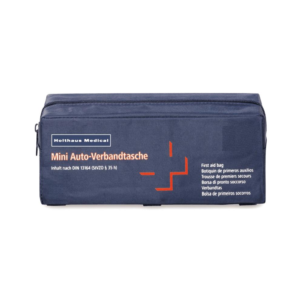 Kompakte, rechteckige Verbandtasche mit dem Aufdruck „Holthaus Medical Mini-Verbandtasche Auto“. Die Tasche ist dunkelblau mit orangem Motiv und enthält medizinisches Zubehör nach DIN 13164. Mehrsprachiger Text weist auf die Erste Hilfe für Autofahrer hin, hergestellt von der Holthaus Medical GmbH & Co. KG.