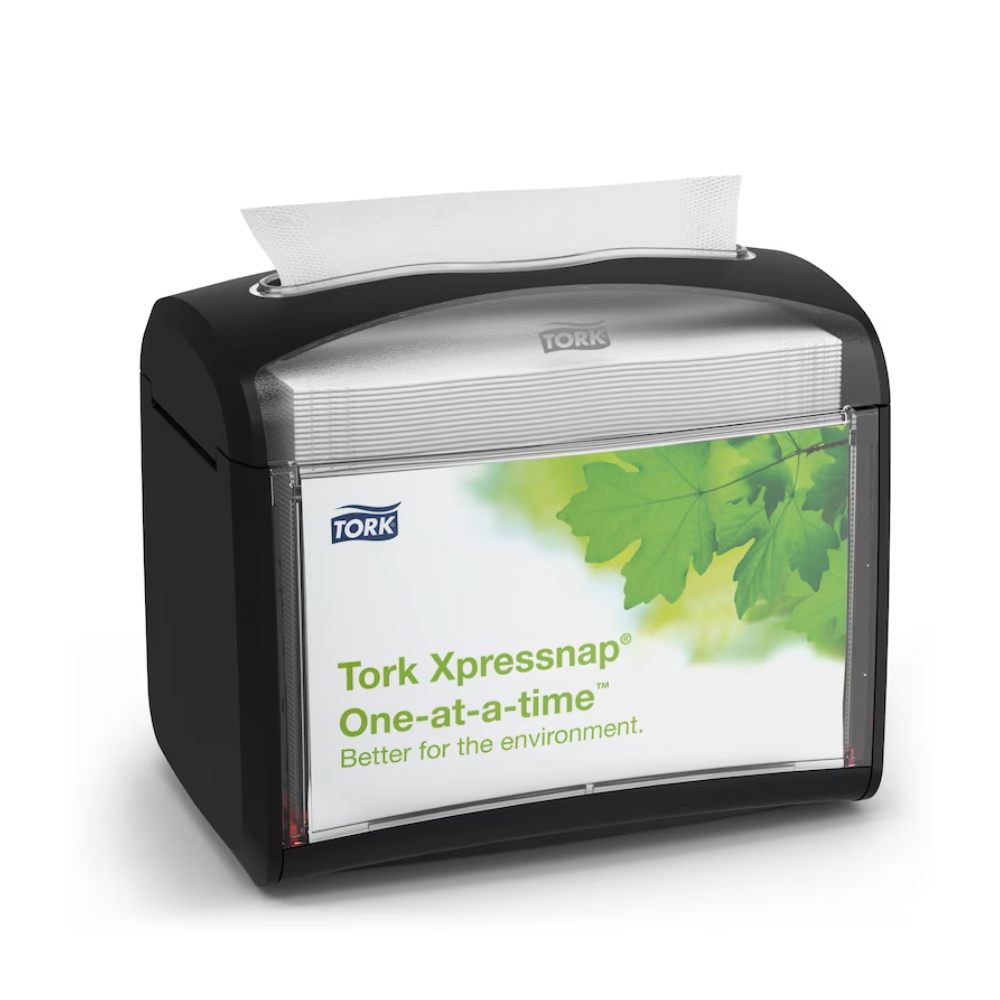 Abgebildet ist ein schwarzer TORK Tork Xpressnap® 272611 Tischspender für Servietten | Karton (4 Packungen) Serviettenspender. Er verfügt über ein klares Frontdisplay mit einem Bild von grünen Blättern und dem Text „Tork Xpressnap, einzeln. Besser für die Umwelt.“ Eine einzelne Serviette ragt sichtbar aus der Oberseite hervor und soll Ihnen helfen, den Serviettenverbrauch zu reduzieren.